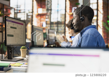 Call center agent tracking shipments in office, looking at PC screen, handling delivery delays. Customer center employee using software to locate clients packages and provide status updates 123808220