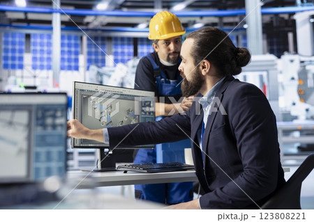 Man in photovoltaics factory talking with manager, diagnosing malfunctioning systems. Solar panels manufacturing plant engineer receiving feedback from manager trying to reduce downtime 123808221