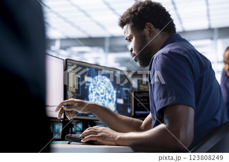 African american man in server farm uses artificial intelligence technology for increased productivity in startup. Machine learning specialist in data center workspace implementing AI driven solutions 123808249