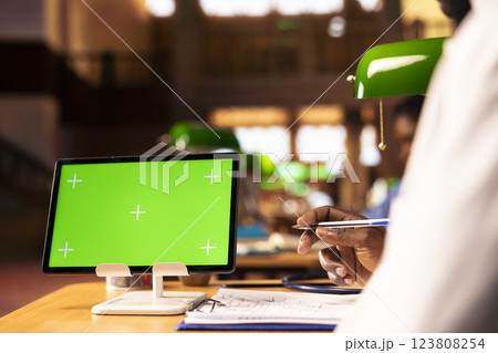 Future healthcare professional studying medical methods next to chroma key screen in an educational library, reading case files and academic papers. Black man works on academic growth. 123808254