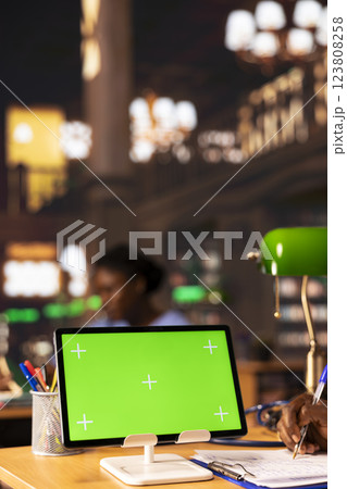 Future healthcare professional studying medical methods next to chroma key screen in an educational library, reading case files and academic papers. Black man works on academic growth. 123808258