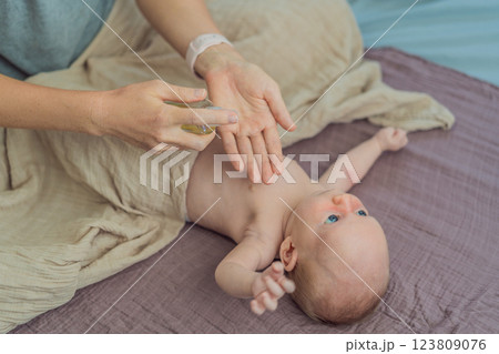 A mother gently massages her 1-month-old baby with baby oil after a bath. This tender moment highlights the bond between parent and child, promoting relaxation, baby care, and the importance of skin 123809076