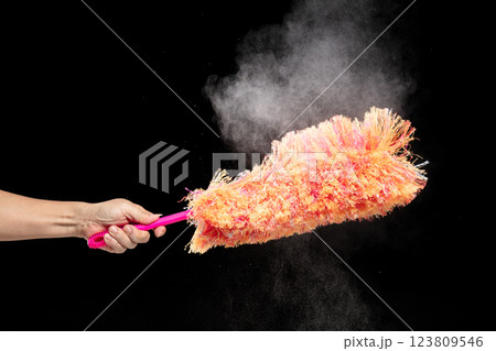 Orange microfiber Duster stick made from synthetic to clean house dust and web. Room Ceiling and window covered with dust bunnies, cobweb cleaned by microfiber duster stick. Black background isolated 123809546