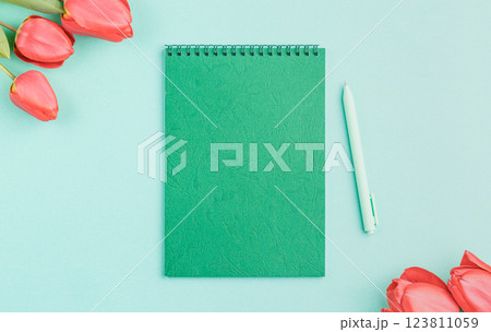 Green notebook with a pen and flowers. 123811059