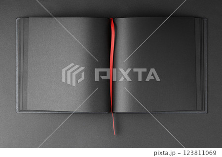 Open notebook with black sheets and red bookmark. Open notebook with black sheets and red bookmark. 123811069