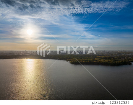 Autumn forest on lake shore at sunset and city on horizon, auerial view 123812525