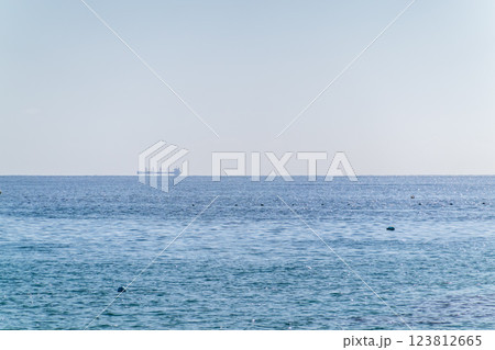 Calm blue sea with the silhouette of a large ship on the horizon 123812665