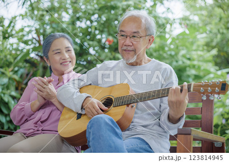 Asian senior couple elderly man playing guitar while his wife singing together outdoors at house, Activity family health care, Enjoying lifestyle during retirement life having fun of senior older Asian senior couple elderly man playing guitar while his wife singing together outdoors at house, Activity family health care, Enjoying lifestyle during retirement life having fun of senior older 123814945
