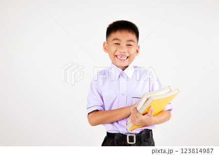 Portrait smile Asian little boy primary posing hand holding book studio isolated white background, happy cute man kid wear school uniform plaid, back to school concept 123814987