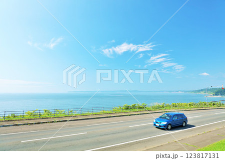 北海道　青空と海沿いの道を走る車 123817131