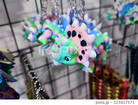 Objects keychains in form of models of toys colorful dinosaur printed on 3D printer from multi-colored molten plastic hanging on chain closeup. Concept 3D Printing. New 3D Printing additive technology 123817571