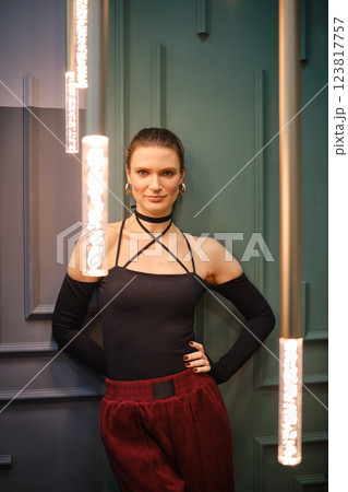 Cheerful woman poses gracefully in a trendy outfit against a stylish contemporary backdrop Cheerful woman poses gracefully in a trendy outfit against a stylish contemporary backdrop 123817757