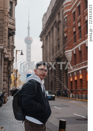 man traveler visiting in Shanghai, China. Happy male Tourist sightseeing Oriental Pearl Tower view in The Rock Bund of Shanghai. landmark and popular for tourism attractions. Travel and Vacation 123818325