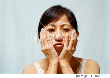 頬に手を当てる中年女性 123821368