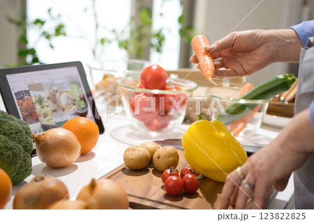 タブレットを見ながら料理をするミドル女性 123822825
