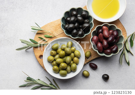 Variety of olives, olive oil, and olive branches served on a wooden board Variety of olives, olive oil, and olive branches served on a wooden board 123823130