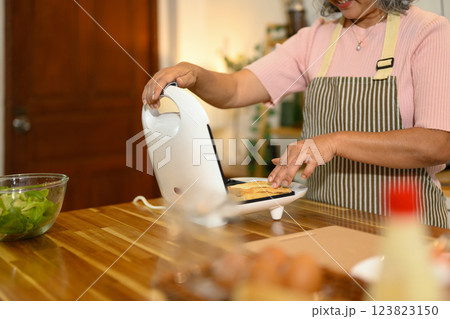 Smiling middle aged woman wearing apron making sandwich in a kitchen 123823150