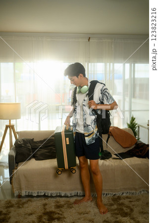 Stylish young man in summer outfit carrying a suitcase preparing to leave for a trip 123823216