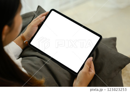 Close up of woman holding digital tablet with an empty screen sitting on a couch 123823253