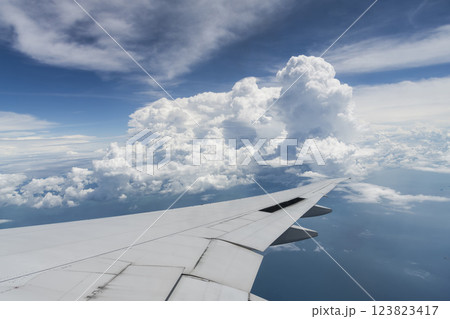 View of the plane's wing and beautiful clouds through the window during the flight. View of the plane's wing and beautiful clouds through the window during the flight. 123823417