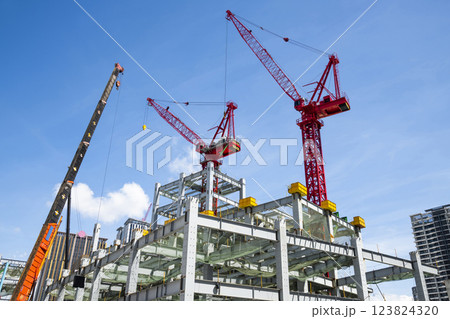 Low-angle view of cranes and steel structures of building construction with a blue sky background in Taiwan. Low-angle view of cranes and steel structures of building construction with a blue sky background in Taiwan. 123824320