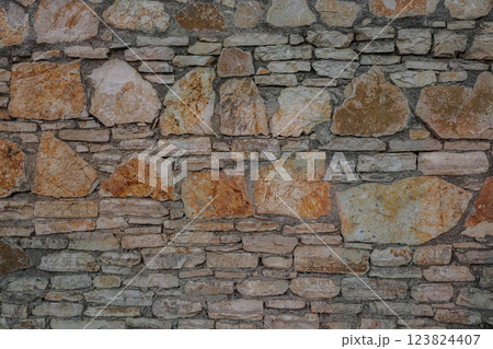 Unique stone wall featuring natural textures in Albania, showcasing a blend of smooth and rough stones with earthy tones 123824407