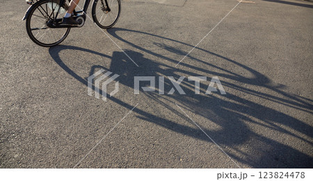 Cyclist casts a long shadow on the pavement in Bucharest as evening light enhances urban life and activity 123824478