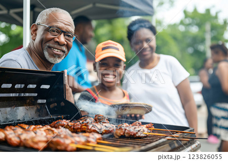 Multigenerational family celebrates Juneteenth outdoors, grilling barbecue joyfully in unity. The summer celebration is filled with food, laughter, and a sense of freedom and culture 123826055