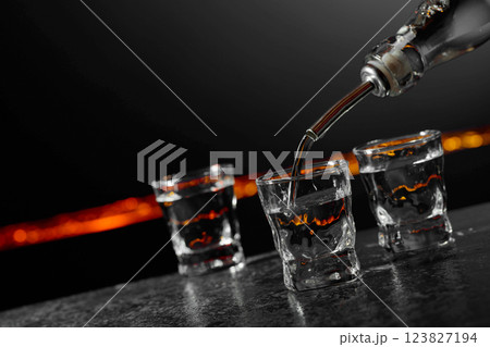 Vodka is poured into a shot glasses. 123827194