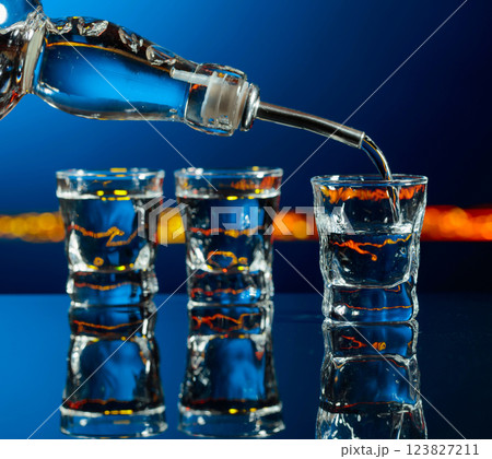 Vodka is poured into a shot glass. 123827211