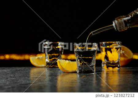Vodka and lemon slices on a black background. 123827212