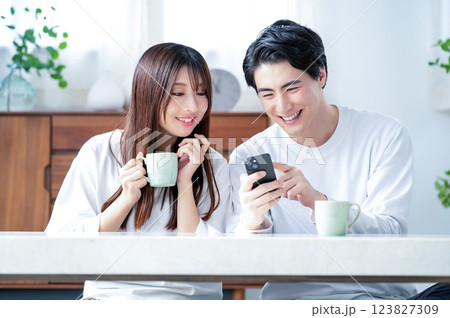 リビングでスマホを持って笑顔の男女 123827309