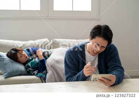 スマホに夢中で看病しない男性 123827322
