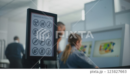 Two Security Officers Monitoring X-ray Images of Baggage Screening on Computer Screens 123827663