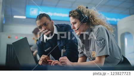 Airport Security Checkpoint: Multiethnic TSA Officers in Headset Using Laptop Computer and Talking Airport Security Checkpoint: Multiethnic TSA Officers in Headset Using Laptop Computer and Talking 123827723