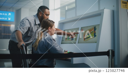 Two Diverse TSA Officers Analyzing X-ray Scanning Images of Baggage Screening on Computer Screens 123827746