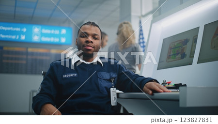 Portrait of TSA Worker Looking at Camera. Computer Screens Showing Baggage Scanning Procedure Portrait of TSA Worker Looking at Camera. Computer Screens Showing Baggage Scanning Procedure 123827831