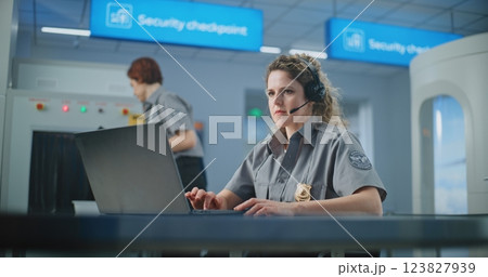 Airport Security Checkpoint: Female TSA Officer Wearing Headset Works on Laptop Airport Security Checkpoint: Female TSA Officer Wearing Headset Works on Laptop 123827939
