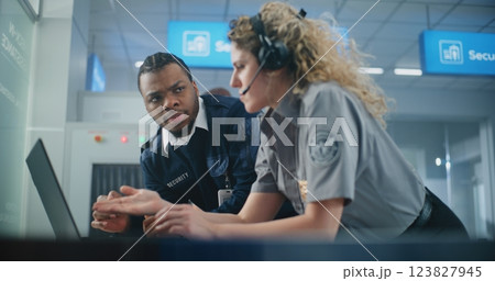 Female Security Officer Wearing Headset Uses Laptop, Talks to Colleague Female Security Officer Wearing Headset Uses Laptop, Talks to Colleague 123827945