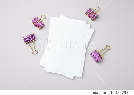 White paper and pink glitter binder clips on gray background 123827985