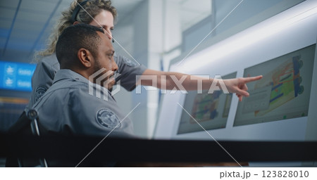 Two Security Officers Analyzing X-ray Scanning Images of Baggage on Computer Screens 123828010