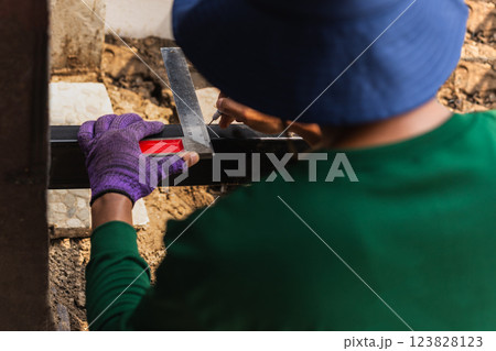Male worker measuring iron with metal ruler in building site. 123828123