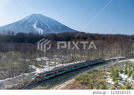 早春の羊蹄山を通過する気動車 123828133