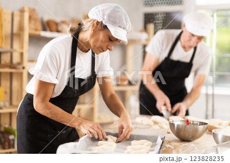 Elderly man and woman molding and cutting pieces of dough 123828235