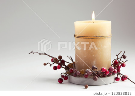 Tranquil and serene candle ambiance with lit white candlelight on a festive berry wreath, creating a warm and cozy atmosphere 123828815
