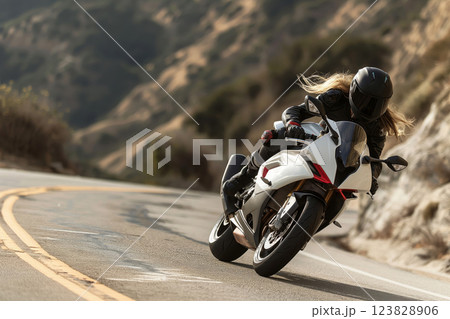 Woman in full protective gear rides a modern sport bike on a curving mountain road, dynamic and focused in her maneuvers 123828906