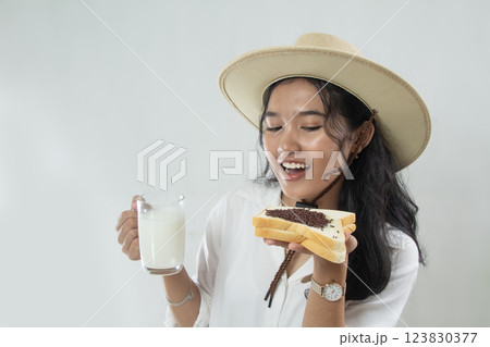 Beautiful young Asian woman in straw hat and showing white bread and milk in her hands, isolated on white 123830377
