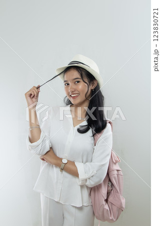 Beautiful young Asian woman tourist in straw hat standing posing with hands holding her beautiful hair facing the camera Beautiful young Asian woman tourist in straw hat standing posing with hands holding her beautiful hair facing the camera 123830721