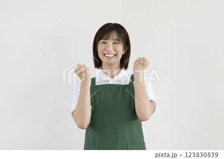 笑顔でガッツポーズをするエプロンをつけたアラサーの女性 カメラ目線 笑顔でガッツポーズをするエプロンをつけたアラサーの女性 カメラ目線 123830839