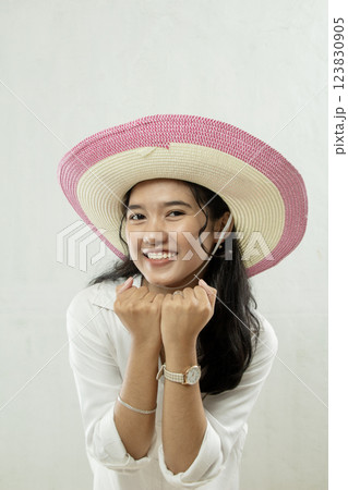 Young Asian woman wearing pink striped straw hat with excited expression running summer vacation, travel advertising studio shoot Young Asian woman wearing pink striped straw hat with excited expression running summer vacation, travel advertising studio shoot 123830905